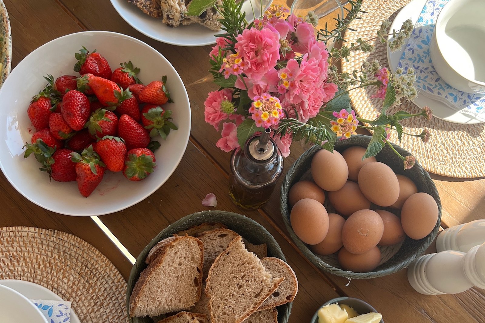Breakfast table with strawberries, bread, eggs and flowers