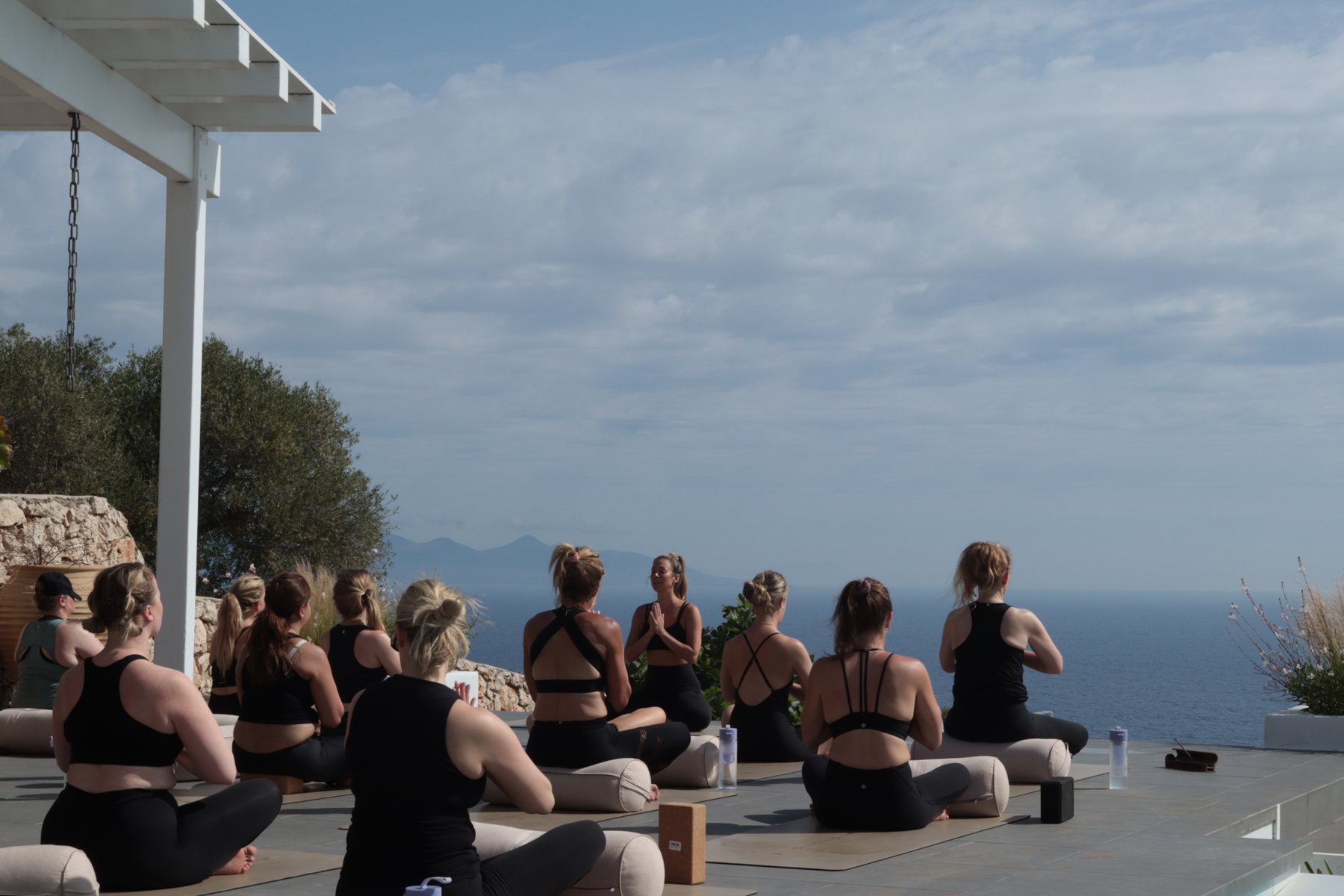 Women sitting for outdoor practice with a sea view
